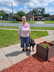 Access Eau Claire Fund Holder Dr. Katherine Schneider and her canine companion Calvin explore REACH's new Community Green Space, which is designed to be accessible to people with disabilities. 